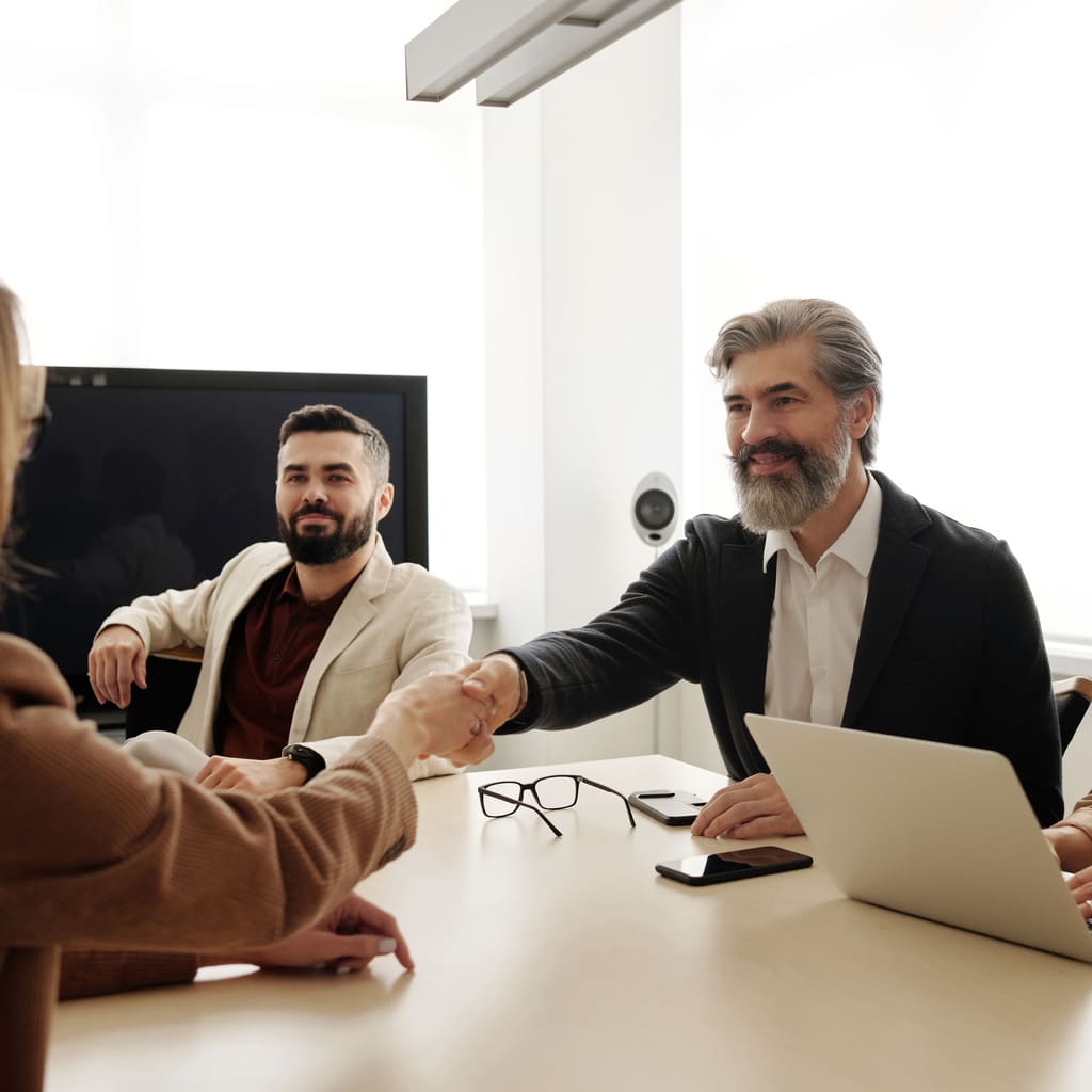 Business people shaking hands across a meeting table.