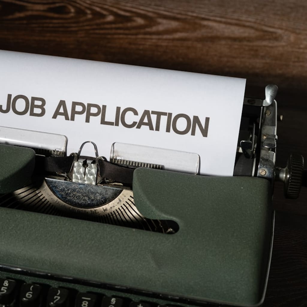 A typewriter holding a sheet of paper labeled job application.