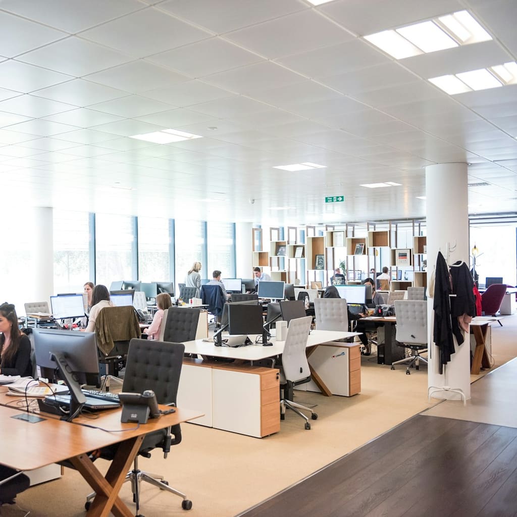 An open-plan office with rows of desks and employees at computers.