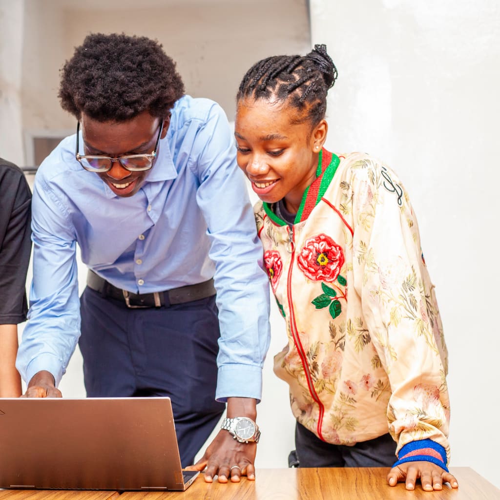 Two colleagues smiling while working together at a laptop.